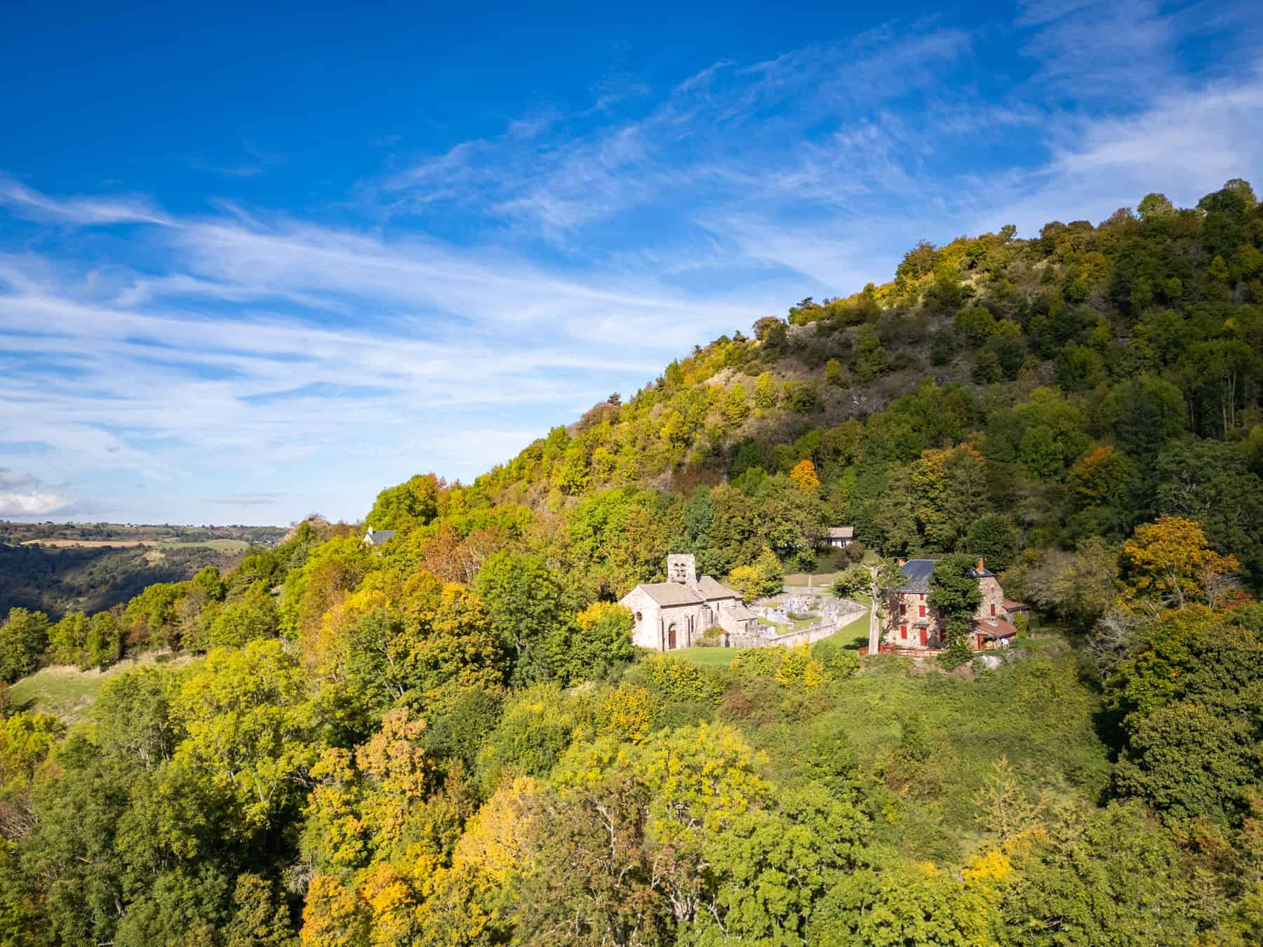 Paysage automnal avec village au pied d'une colline verdoyante.