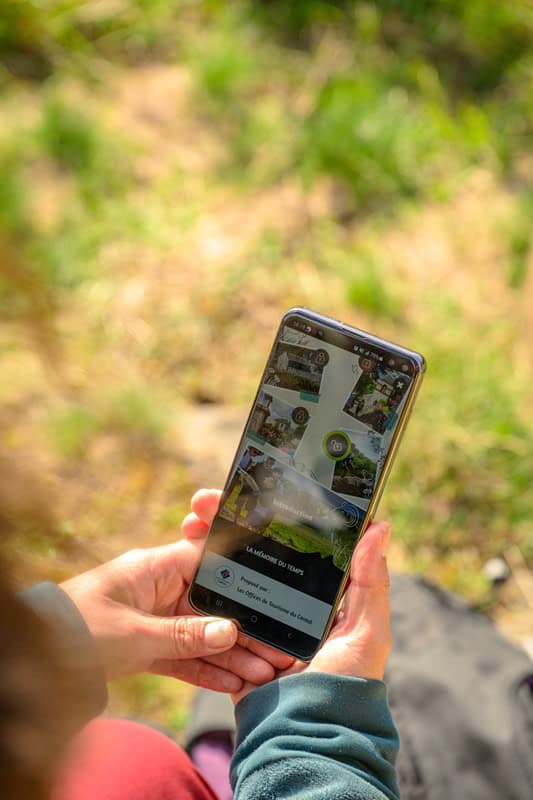 Person utilisant un smartphone pour explorer la nature dans les Hautes Terres Tourisme.