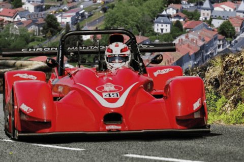 Voiture de course rouge sur route de montagne dans les Hautes Terres.