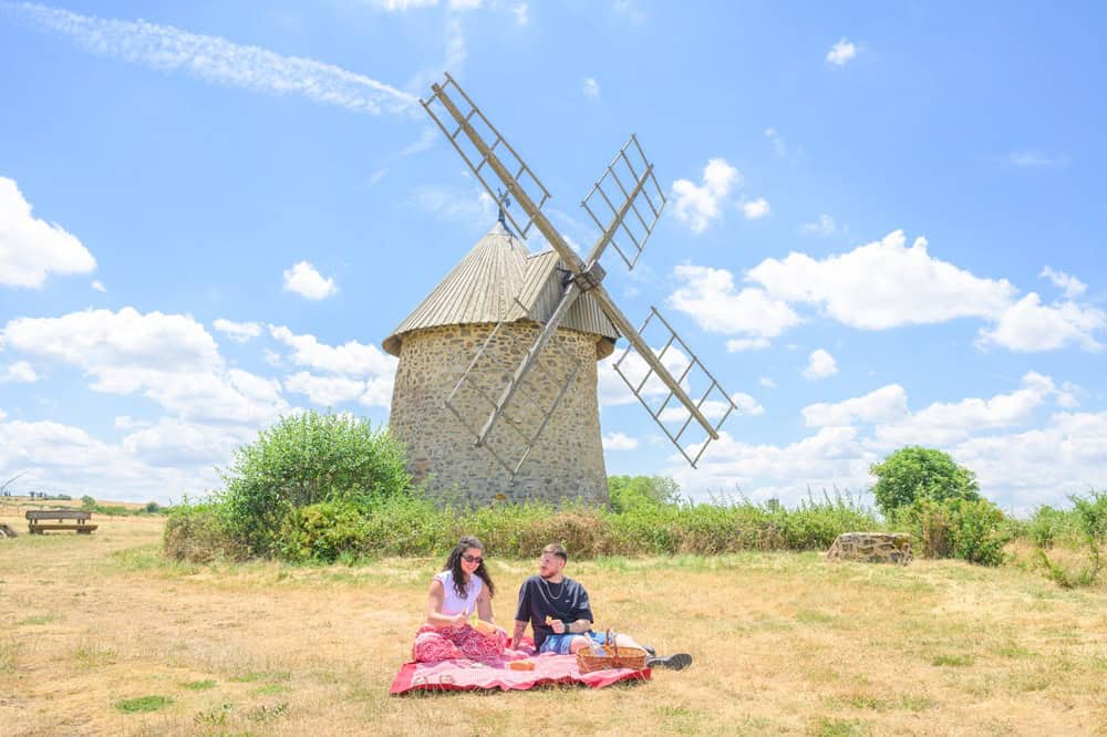 Moulin à vent traditionnel dans un paysage rural ensoleillé.