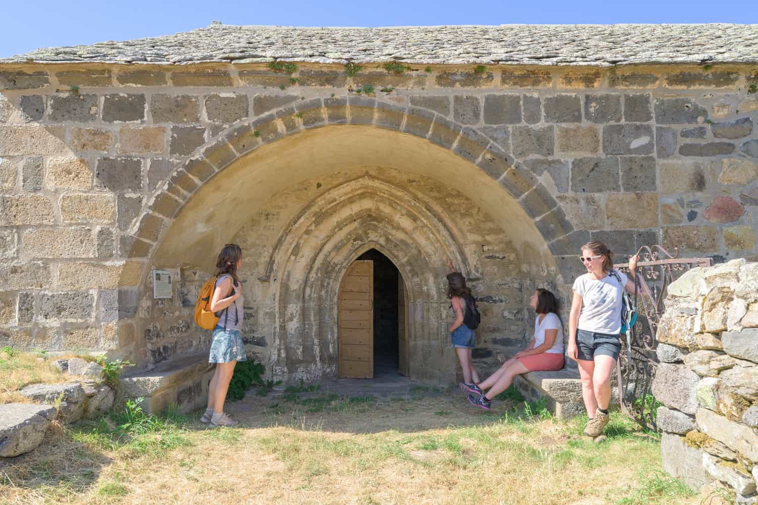 Groupe de jeunes devant une ancienne porte d'église en pierre.