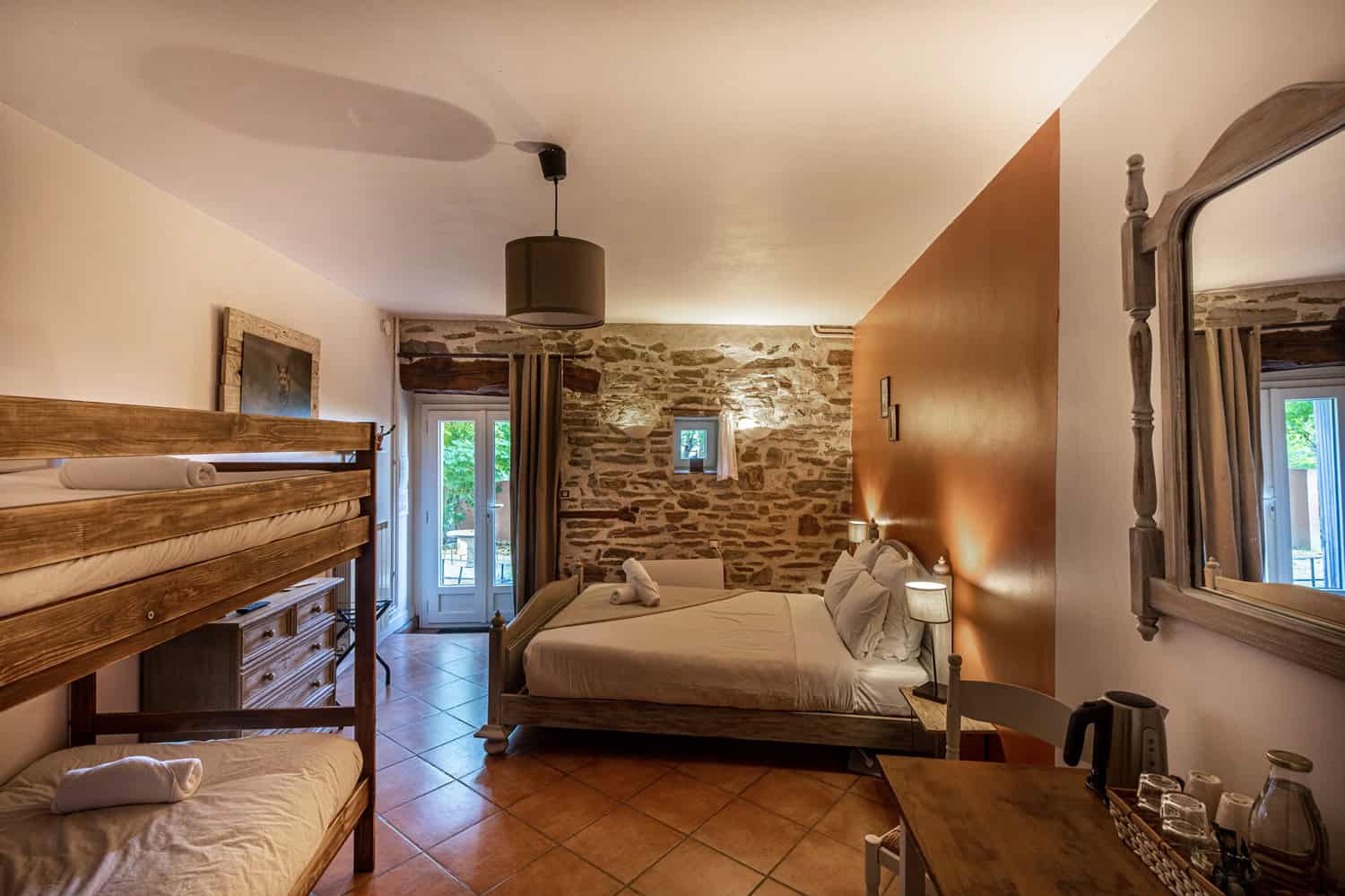 Chambre chaleureuse avec lit double, mobilier en bois et mur en pierre.