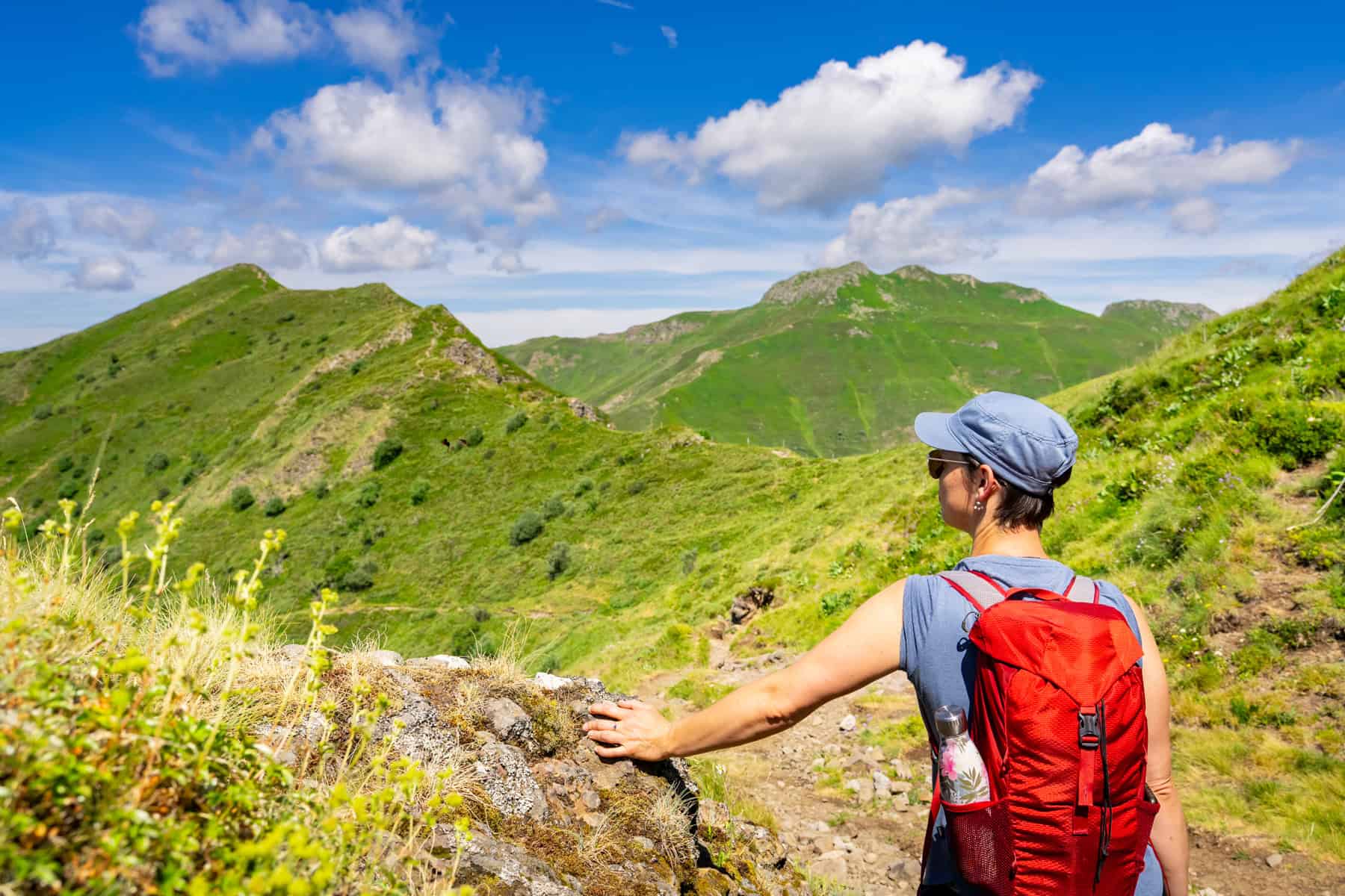 Randonneuse admirant le paysage verdoyant des monts du Cantal.