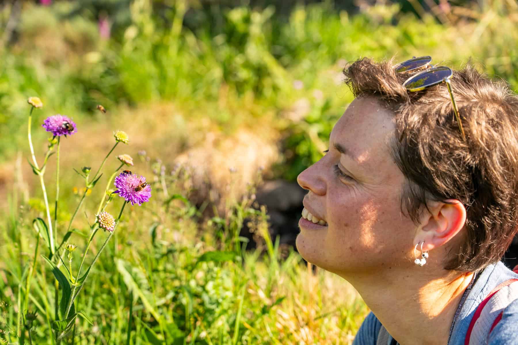 Femme souriante appréciant la nature et les fleurs sauvages en plein air.