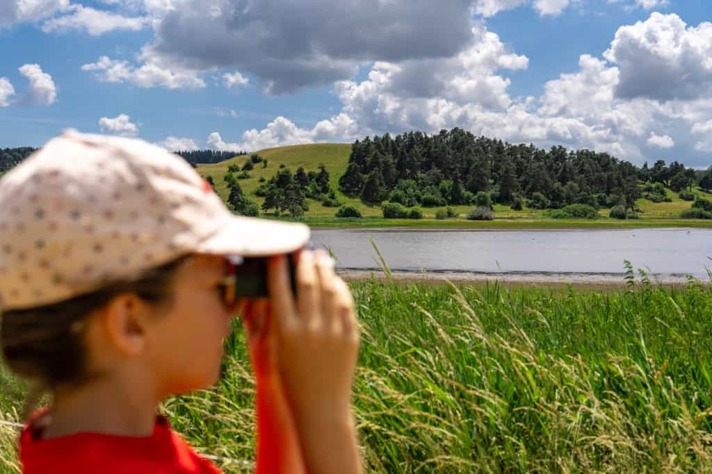 Jeune enfant observant la nature avec des jumelles dans le Massif de la Pinatelle.