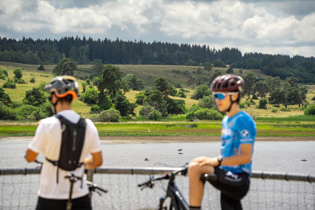 Deux cyclistes en pleine nature près d'un lac dans le Massif de la Pinatelle.
