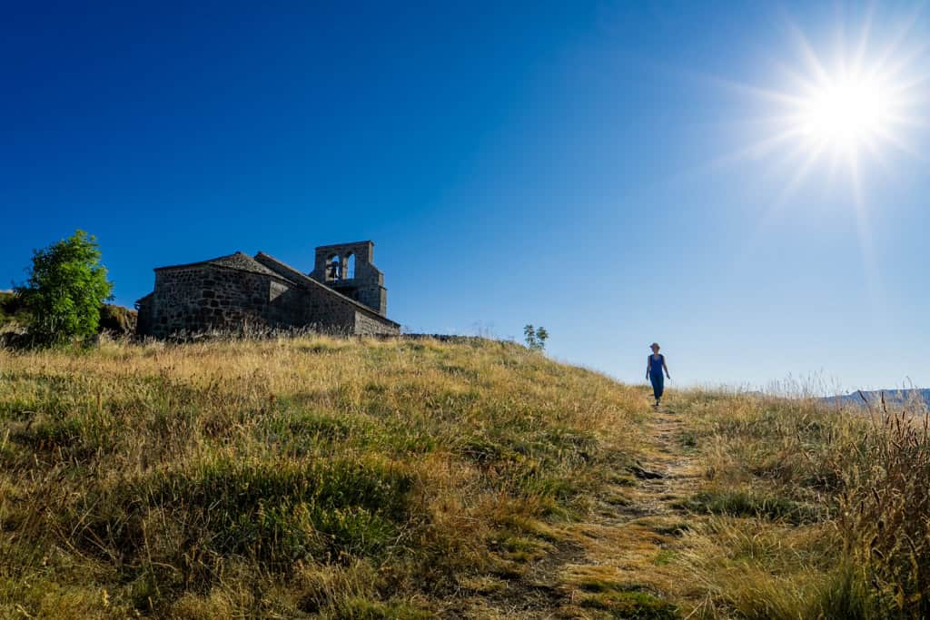 Chapelle perchée dans un paysage ensoleillé avec un sentier.