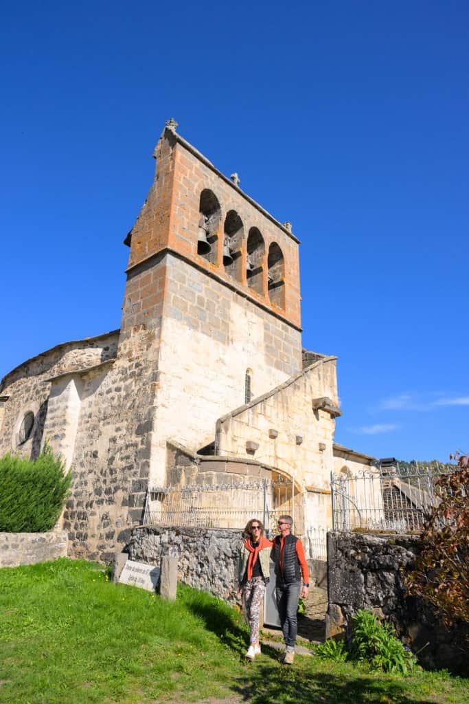 Touristes devant une ancienne tour d'église en pierre dans un site historique.