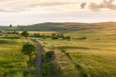 Paysage rural avec train et collines au coucher du soleil.